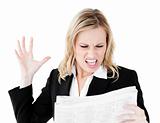 Angry businesswoman looking at a newspaper shouting