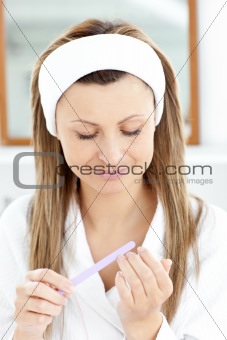 Beautiful woman filing her nails in the bathroom