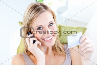 Bright woman ordering on the phone lying on a sofa