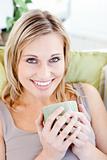 Positive blond woman holding a cup smiling at the camera