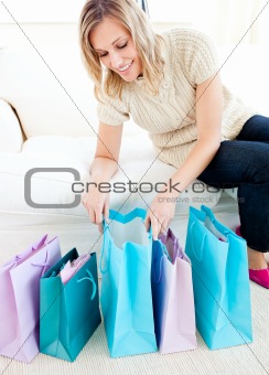 Cheerful woman lying on a white couch with shopping bags on the ground
