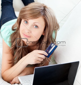 Close-up of a attractive woman lying ona sofa holding a card and