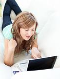Joyful blond woman looking at her laptop on the sofa 