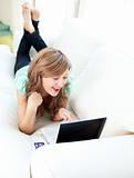 Cheerful caucasian woman lying on the sofa with laptop and card in the living room