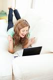 Enthusiastic caucasian woman looking at her laptop on the sofa 