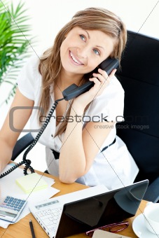 Self-assured businesswoman talking on phone sitting at her desk