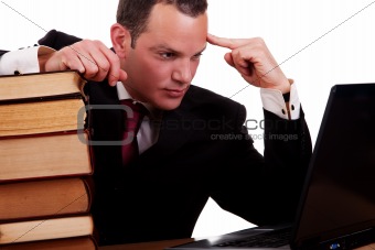 businessman on desk with books, looking at the computer