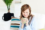 Relaxed businesswoman enjoying her coffee sitting on a sofa 