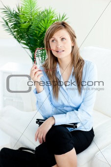 Pensive businesswoman holding glasses sitting on a sofa