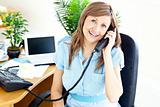 Lively young businesswoman talking on phone sitting at her desk 
