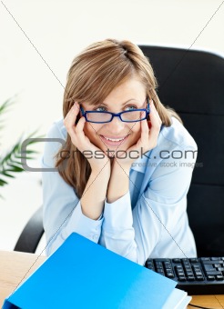 Delighted young businesswoman sitting at her desk in the office 