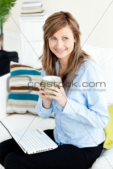 Captivating blond businesswoman holding a coffee sitting on a so