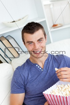 Laughing caucasian man eating popcorn looking at the camera 