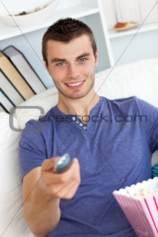 Positive caucasian man holding a remote looking at the camera 