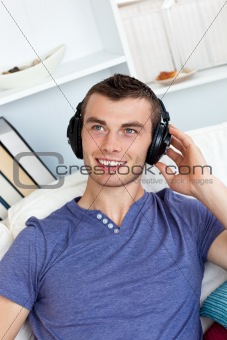 Lively young man listening to music sitting on the couch 
