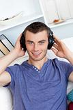 Relaxed young man listening to music looking at the camera 