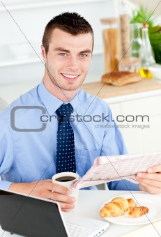 Handsome businessman reading the newspaper drinking coffee 