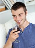 Animated young man drinking wine sitting on the sofa 
