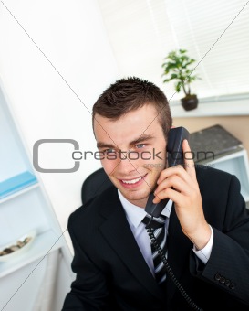Caucasian young businessman talking on phone sitting at his desk