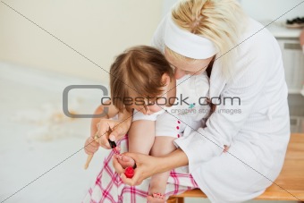 Concentrated mother making her little daughter's nails 