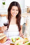 Positive asian woman holding a glass of wine having dinner 