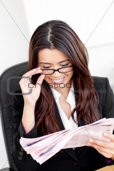 serious asian business woman reading the newspaper in her office