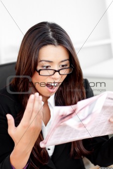 Shocked asian businesswoman looking at the newspaper 