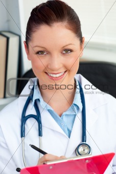 Confident female doctor smiling at the camera holding a clipboar