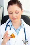 Serious young female doctor looking at pills 