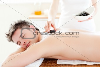 Charming young man receiving a massage with hot stone 