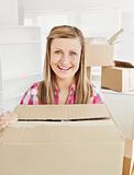 Positive woman holding a box standing in her new house looking a