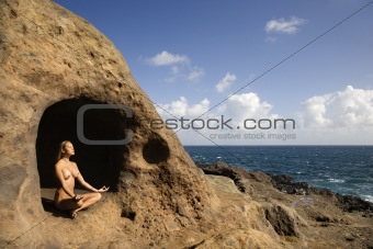 Woman meditating in cave.