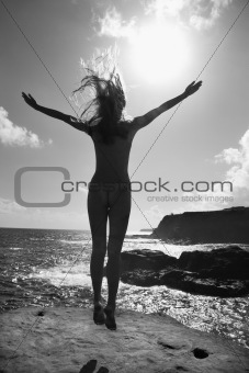 Nude woman jumping on beach.