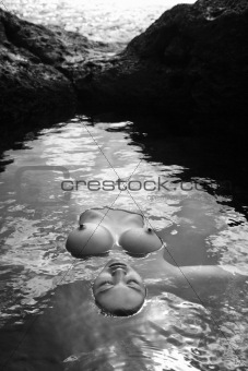 Nude woman floating in water.