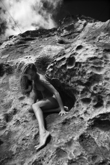 Nude woman sitting on rock.