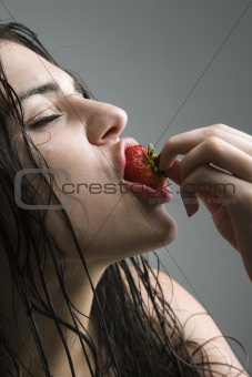 Woman biting strawberry.