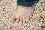 Male foot on beach.