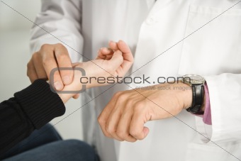 Doctor taking patient's pulse.