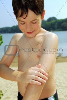 Boy applying sunscreen