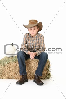 Country boy sitting on lucerne bale