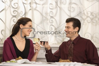 Couple toasting glasses at dinner.