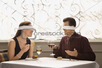 Couple dining wearing blindfolds.
