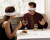Couple dining wearing blindfolds.