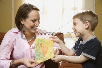Boy giving mom a drawing.