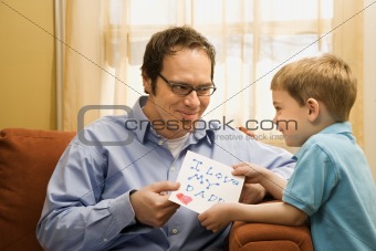 Boy giving dad drawing.