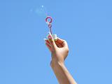 Female hand and soap bubbles on a background of the blue sky