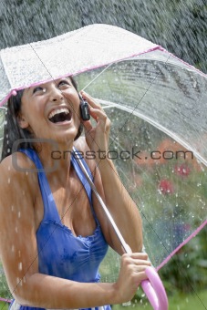 Young Woman Using a Cellphone and Umbrella in Rain