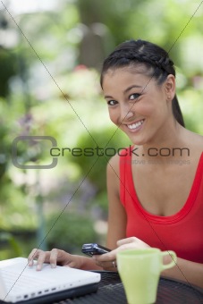 Beautiful Young Woman Using a Cellphone and Laptop Outdoors