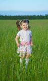 Happy child jumps on green grass in field