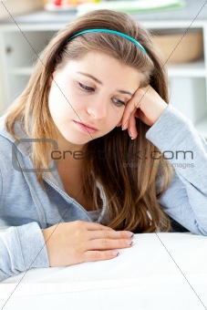 Dejected young woman sitting at the table in the kitchen 